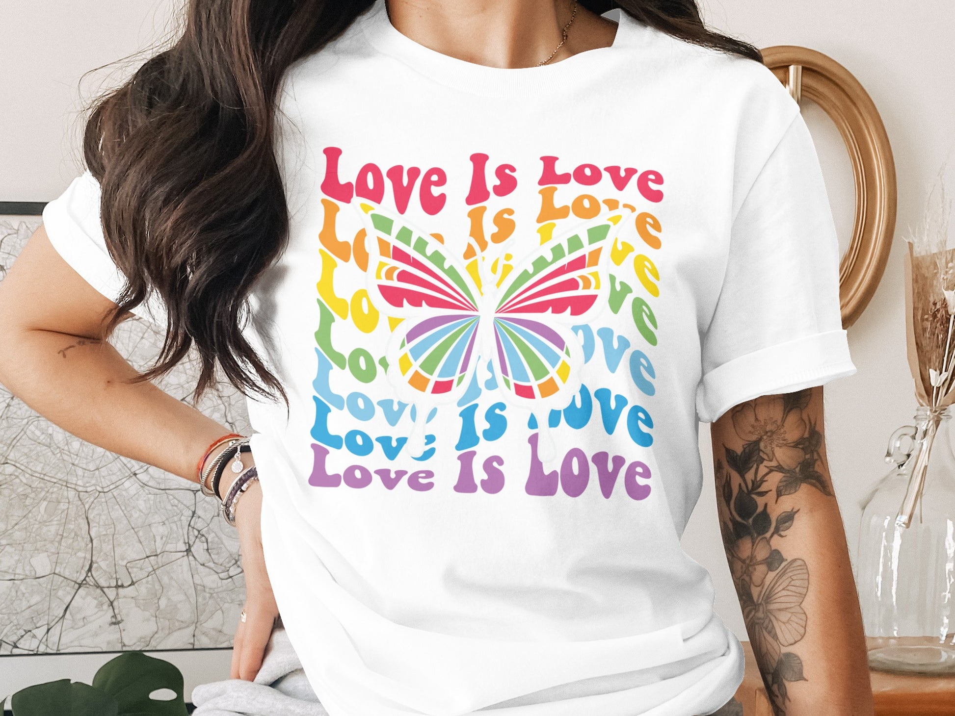 White t-shirt with "Love Is Love" repeated in rainbow colors around a butterfly.