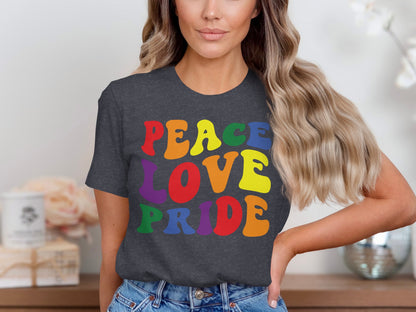 Dark t-shirt with "Peace Love Pride" in rainbow gradient letters.