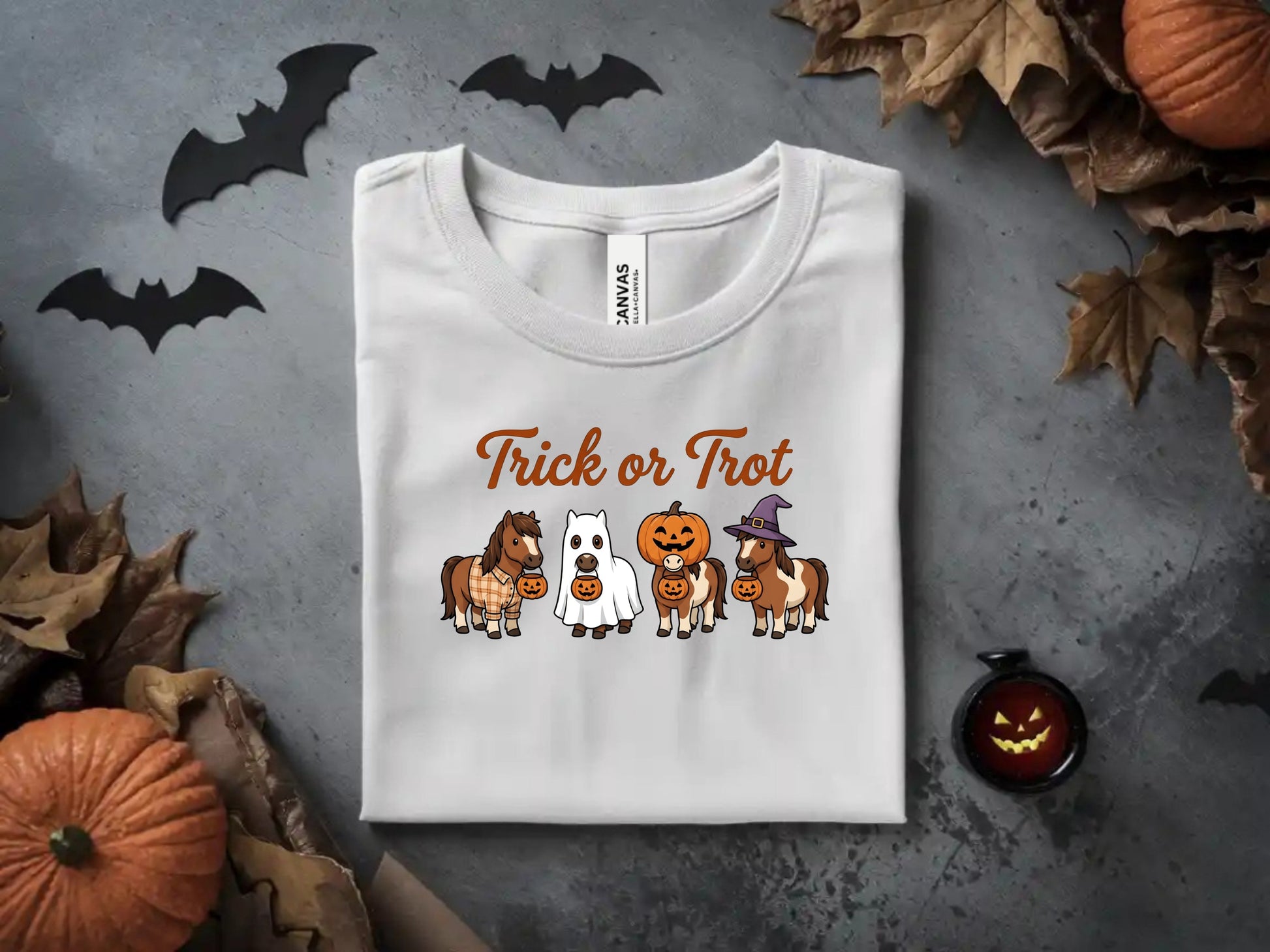 White t-shirt with "Trick or Trot" Halloween graphic featuring four ponies.