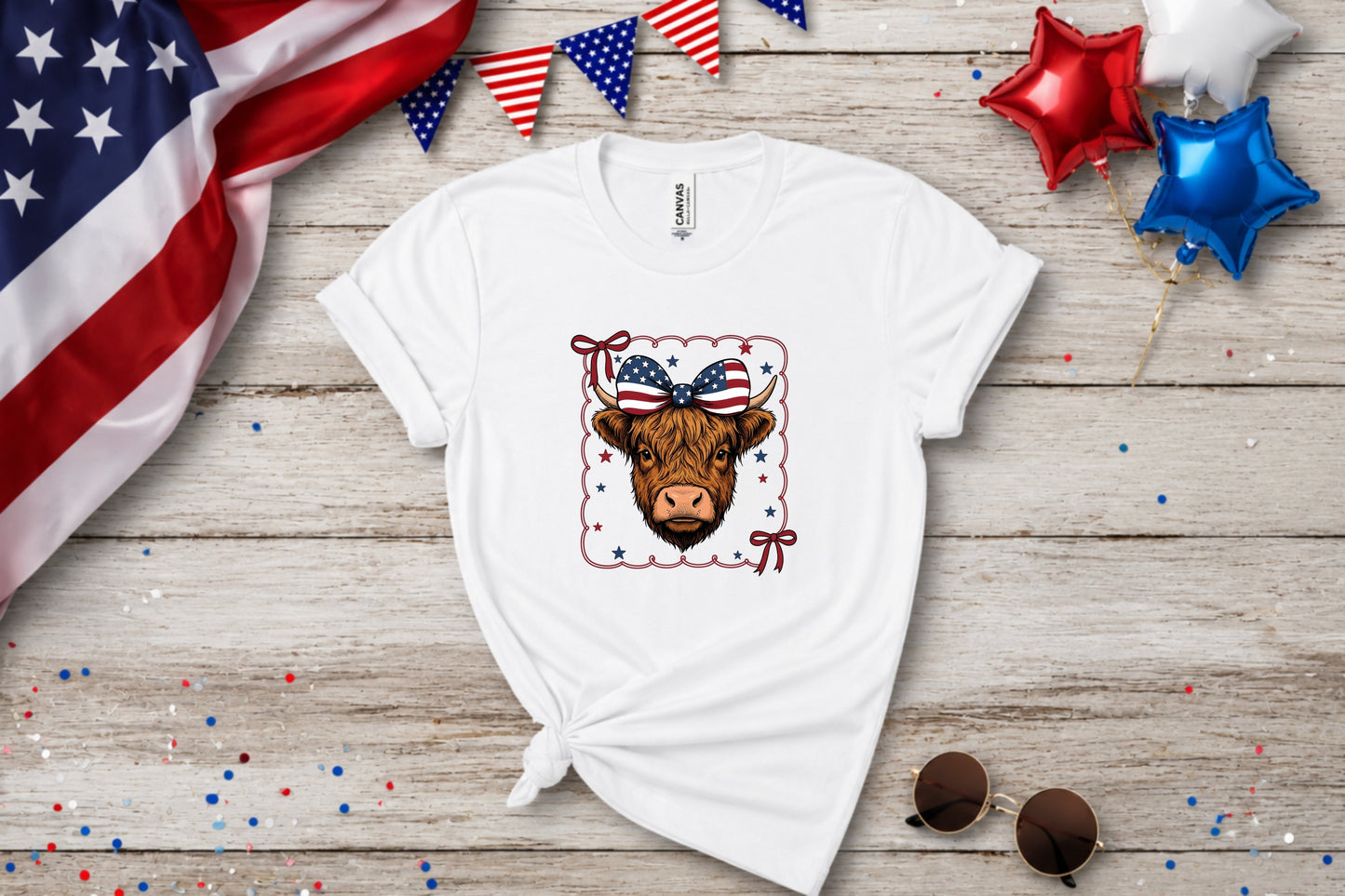 White t-shirt with a Highland cow wearing a patriotic bow and stars.