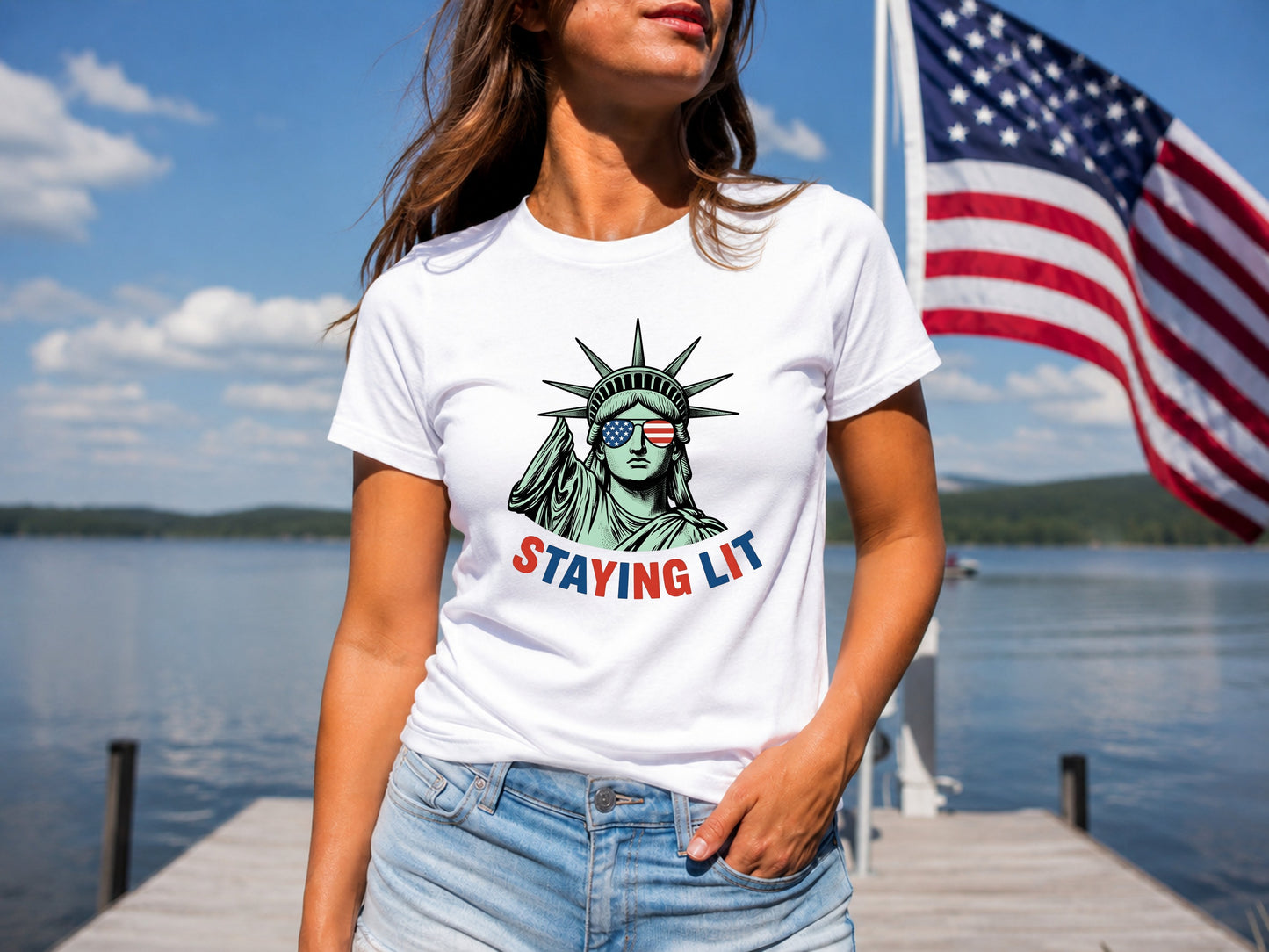 Woman wearing white t-shirt with "STAYING LIT" and Statue of Liberty graphic.