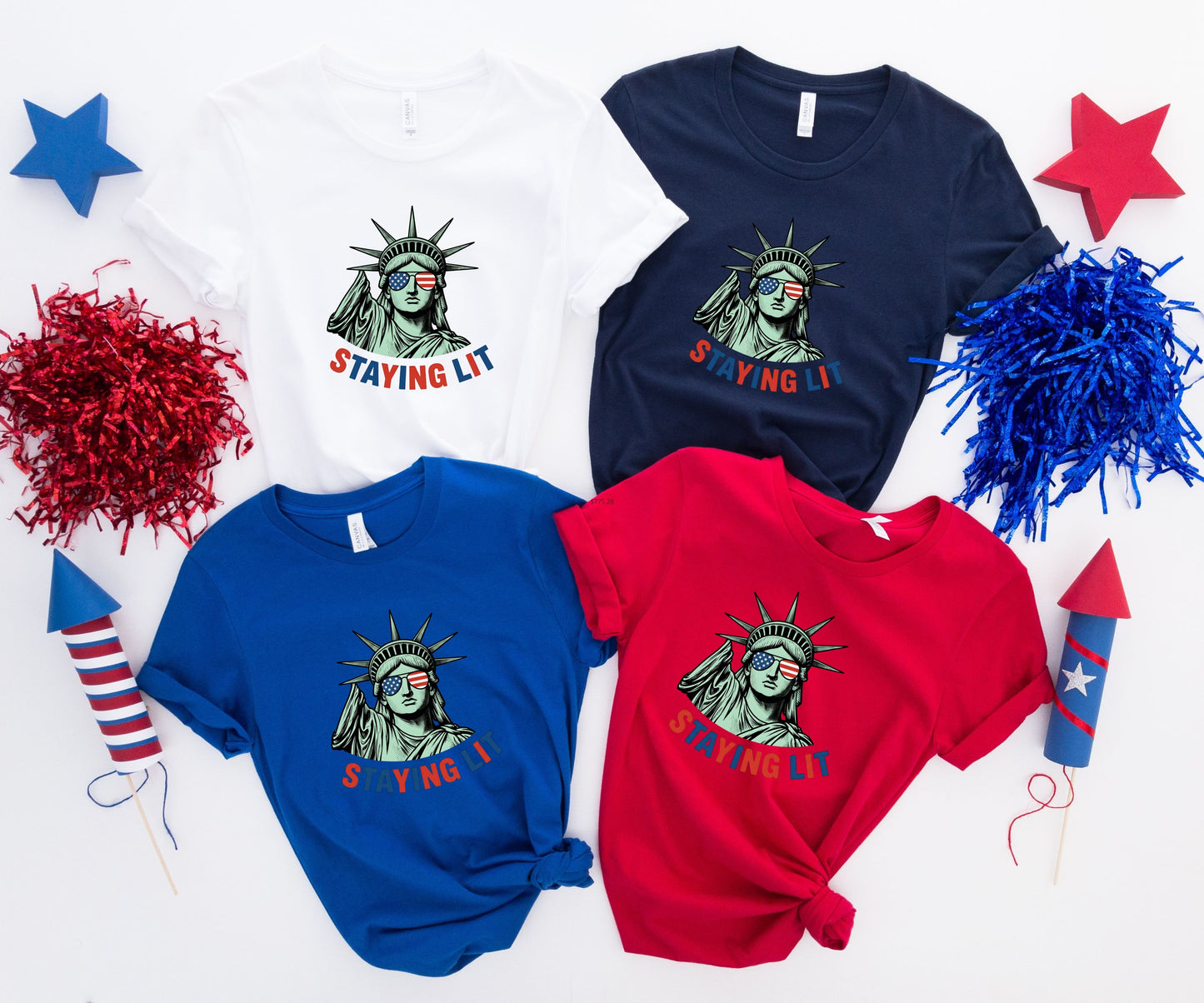 Four t-shirts featuring the Statue of Liberty and "STAYING LIT" text.