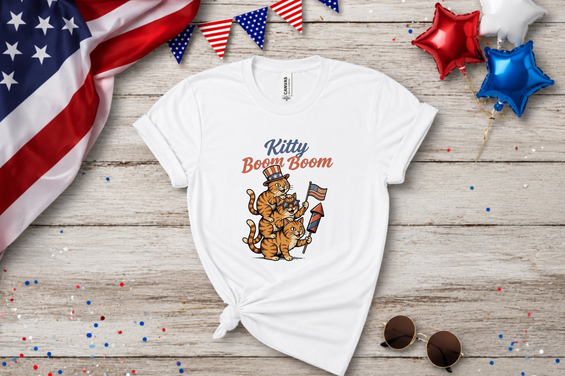 White t-shirt with cartoon cats holding fireworks and wearing patriotic hats.