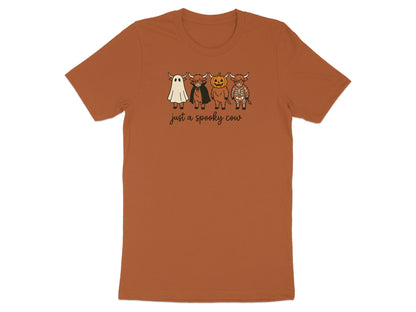 Brown t-shirt with white cartoon highland cows dressed as a ghost, vampire, pumpkin, and skeleton.