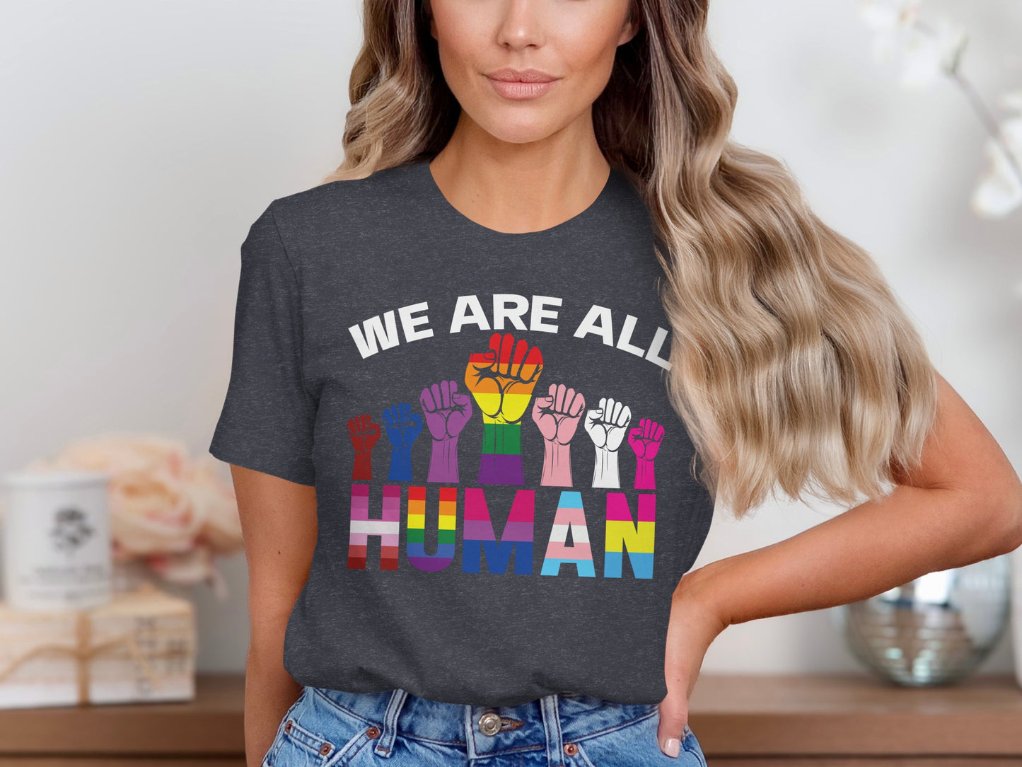 Woman wearing t-shirt with rainbow fists and "WE ARE ALL HUMAN" text.
