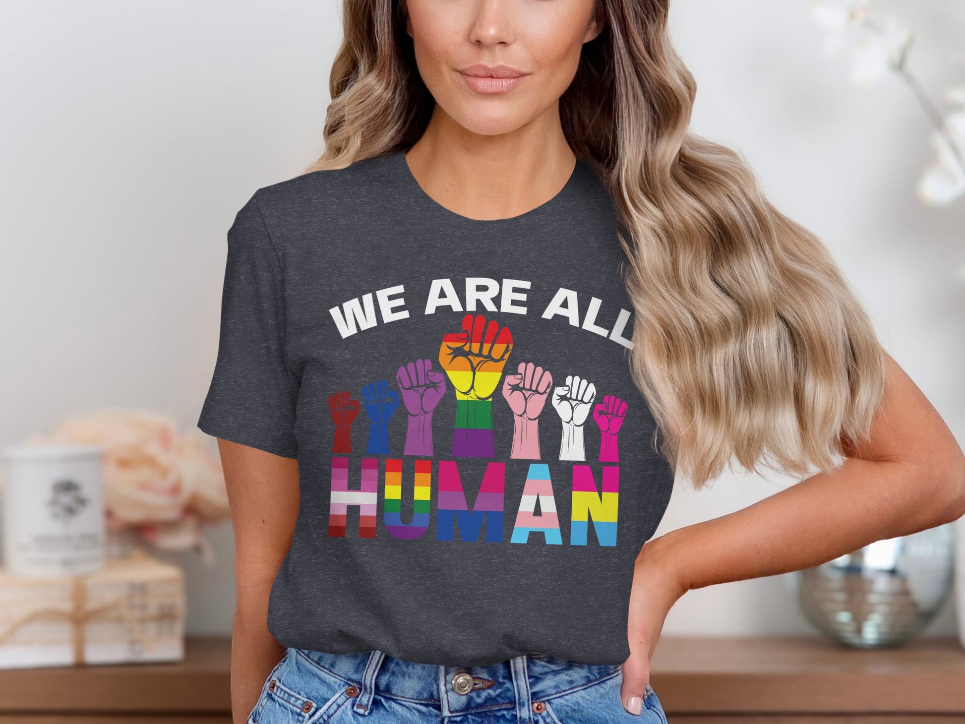 Woman wearing t-shirt with rainbow fists and "WE ARE ALL HUMAN" text.