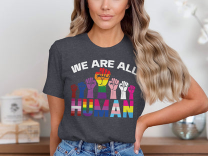 Woman wearing t-shirt with rainbow fists and "WE ARE ALL HUMAN" text.