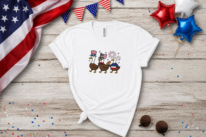 White t-shirt with patriotic ducks wearing hats and glasses with fireworks.