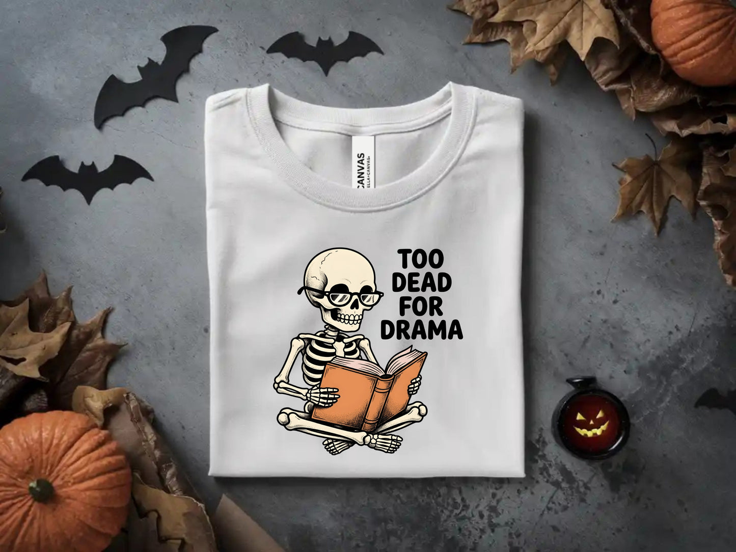White t-shirt with skeleton reading a book, text "TOO DEAD FOR DRAMA".