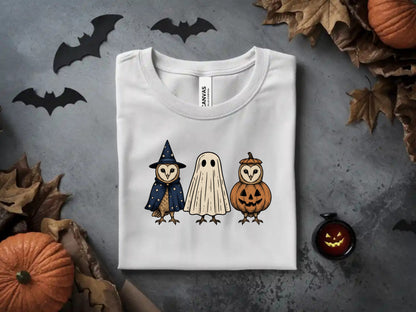 White t-shirt with Halloween owls dressed as a wizard, ghost, and pumpkin.