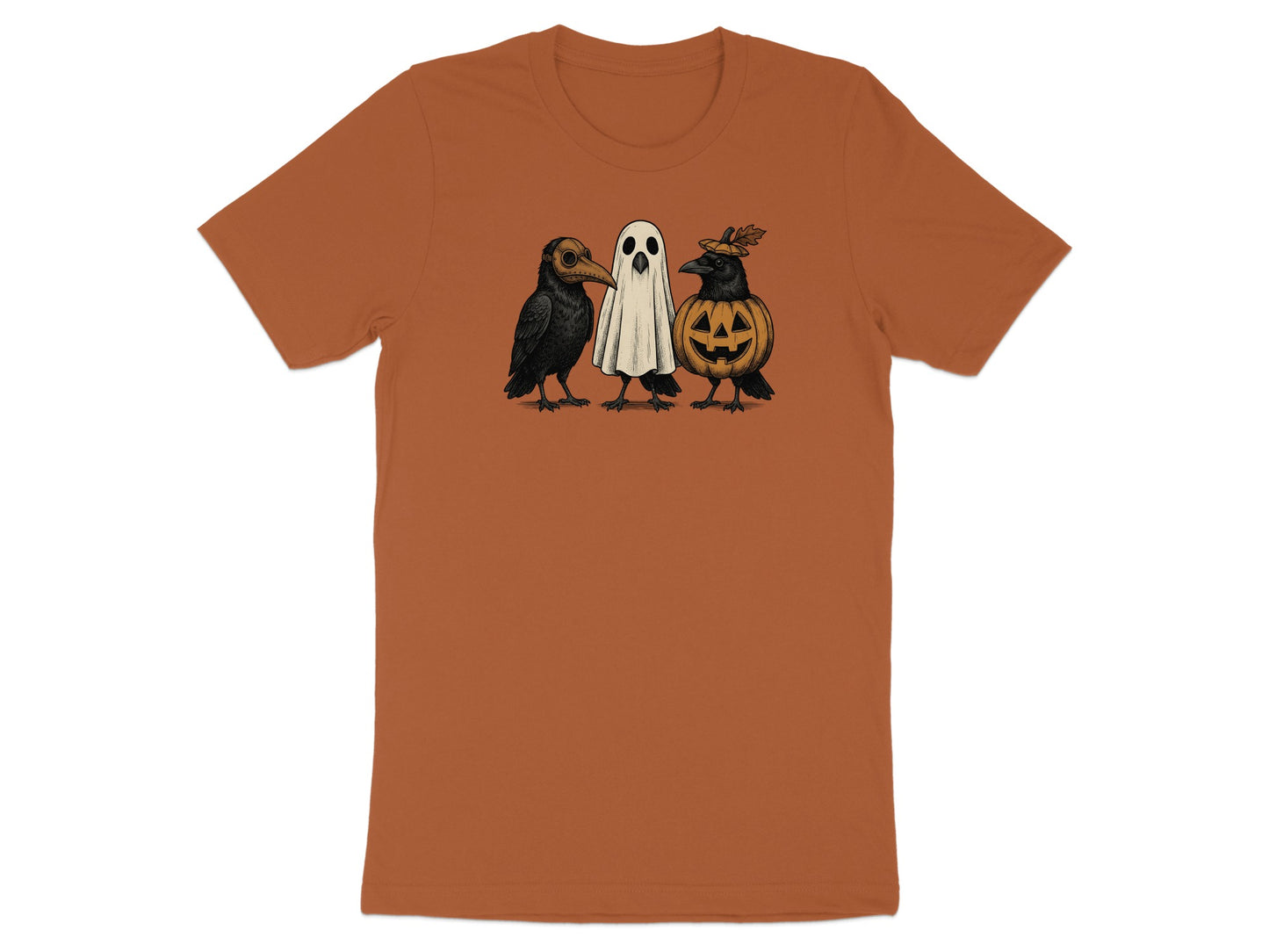 Three Halloween creatures: two crows and a ghost, on a burnt orange t-shirt.