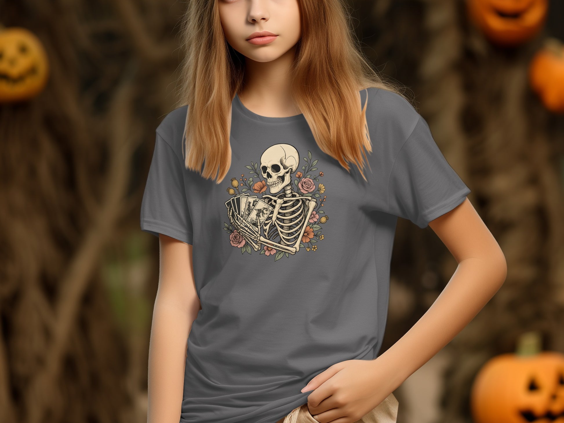 Woman wearing a grey t-shirt with a skeleton and floral design, with pumpkins in background