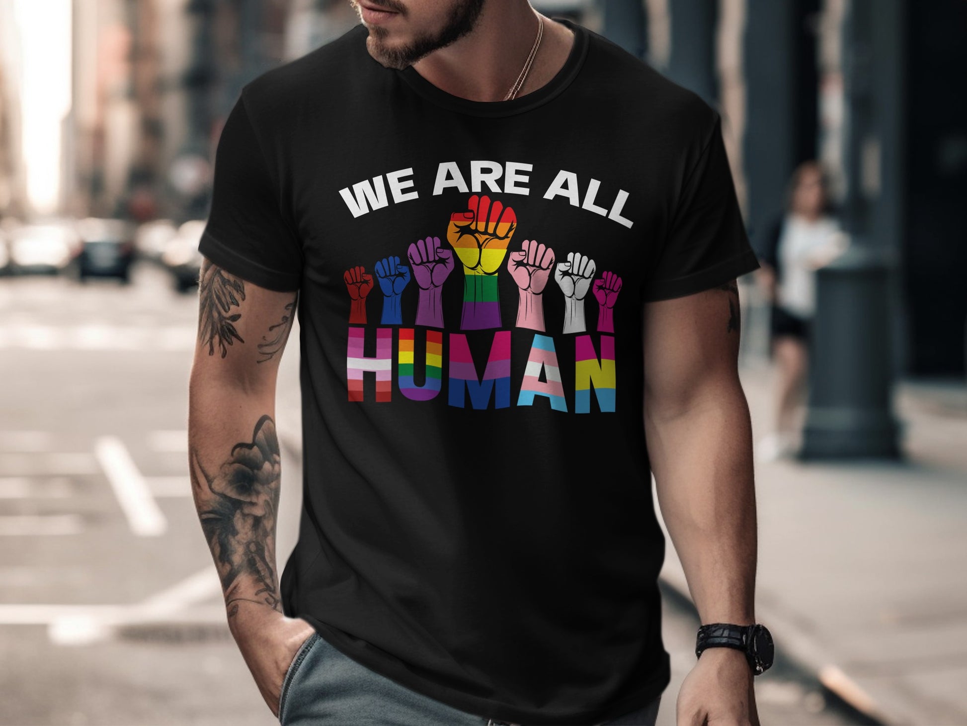 Black t-shirt with "WE ARE ALL HUMAN" text and rainbow-colored raised fists.