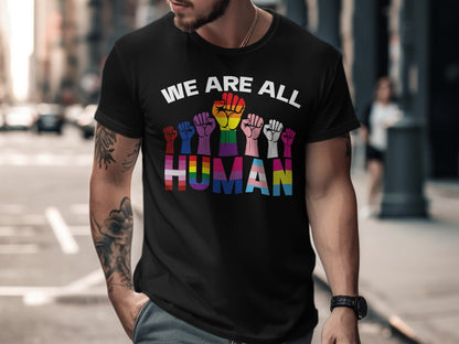 Black t-shirt with "WE ARE ALL HUMAN" text and rainbow-colored raised fists.