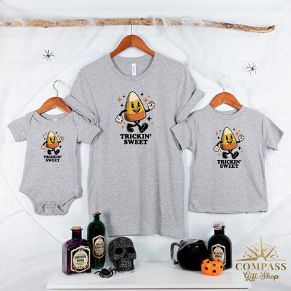 Three grey Halloween graphic tees with candy corn character and "Trickin' Sweet" text.