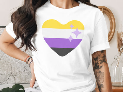 White t-shirt with a nonbinary pride heart graphic and sparkling accents.