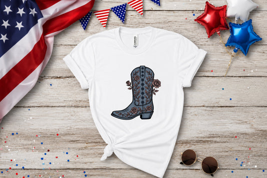 White t-shirt with a faded blue cowboy boot and rose graphic, patriotic decorations.