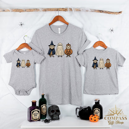 Three grey t-shirts and a baby onesie feature owls dressed as a witch, a ghost, and a pumpkin.