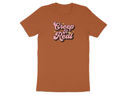 Brown t-shirt with pink "Creep It Real" graphic and stars.