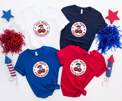 Four t-shirts: white, navy, blue, and red, each with "little Miss Firecracker" graphic.