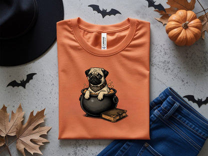 Orange t-shirt with pug in cauldron Halloween graphic and a small book.
