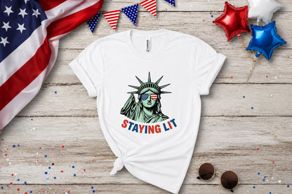 White t-shirt with Statue of Liberty wearing sunglasses and "STAYING LIT" text.