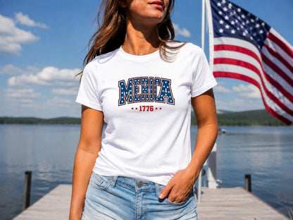 Woman wearing white "America 1776" t-shirt and denim shorts by lake.