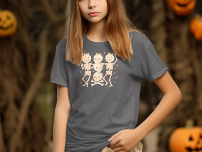 Gray t-shirt with dancing skeletons and skulls graphic, with pumpkins in background.