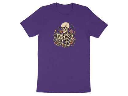 Skeleton holding playing cards surrounded by flowers on a purple t-shirt.