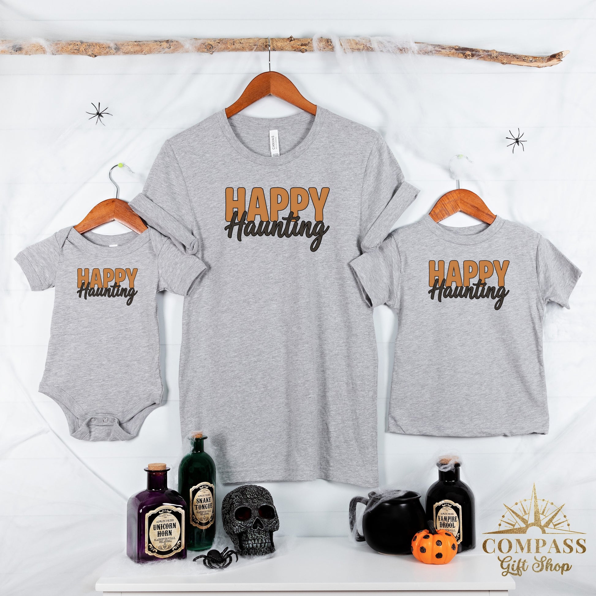 Grey t-shirts and baby onesie with "HAPPY Haunting" text; Halloween props displayed.