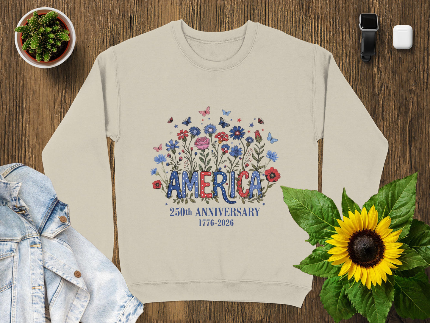 Cream sweatshirt with "AMERICA 250TH ANNIVERSARY 1776-2026" text and floral design.