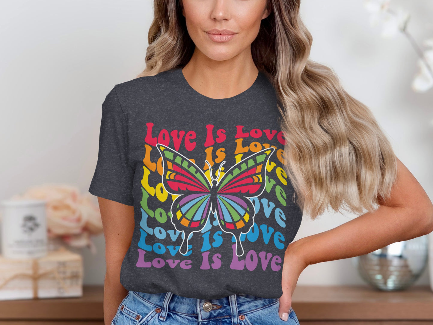 Woman wearing a dark grey t-shirt with a rainbow butterfly and "Love Is Love" text.