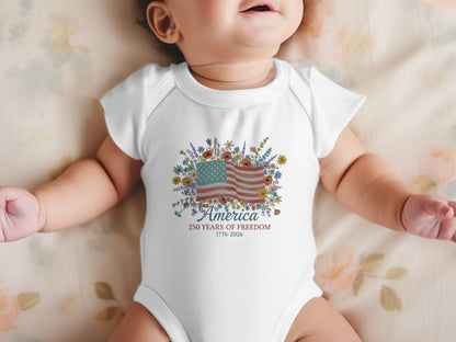Baby onesie with American flag and floral design, text "America 1776-2026".