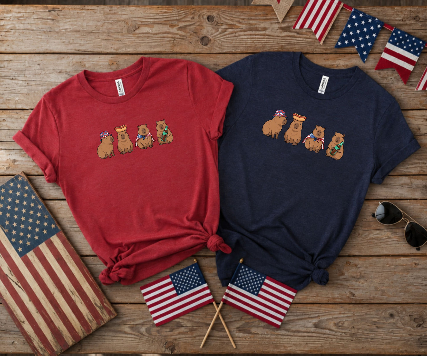Two t-shirts featuring capybaras wearing party hats with hot dogs.