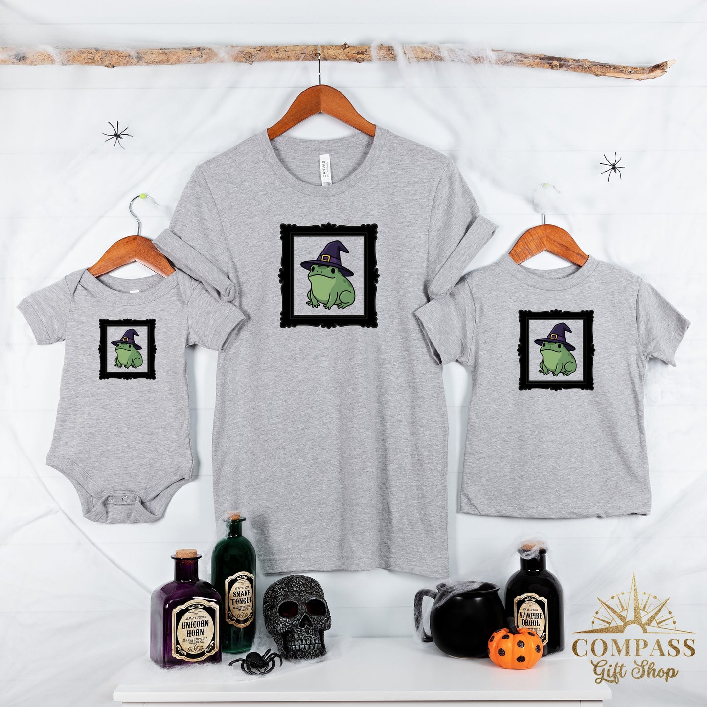 Grey t-shirts and a bodysuit feature a frog in a witch hat graphic.