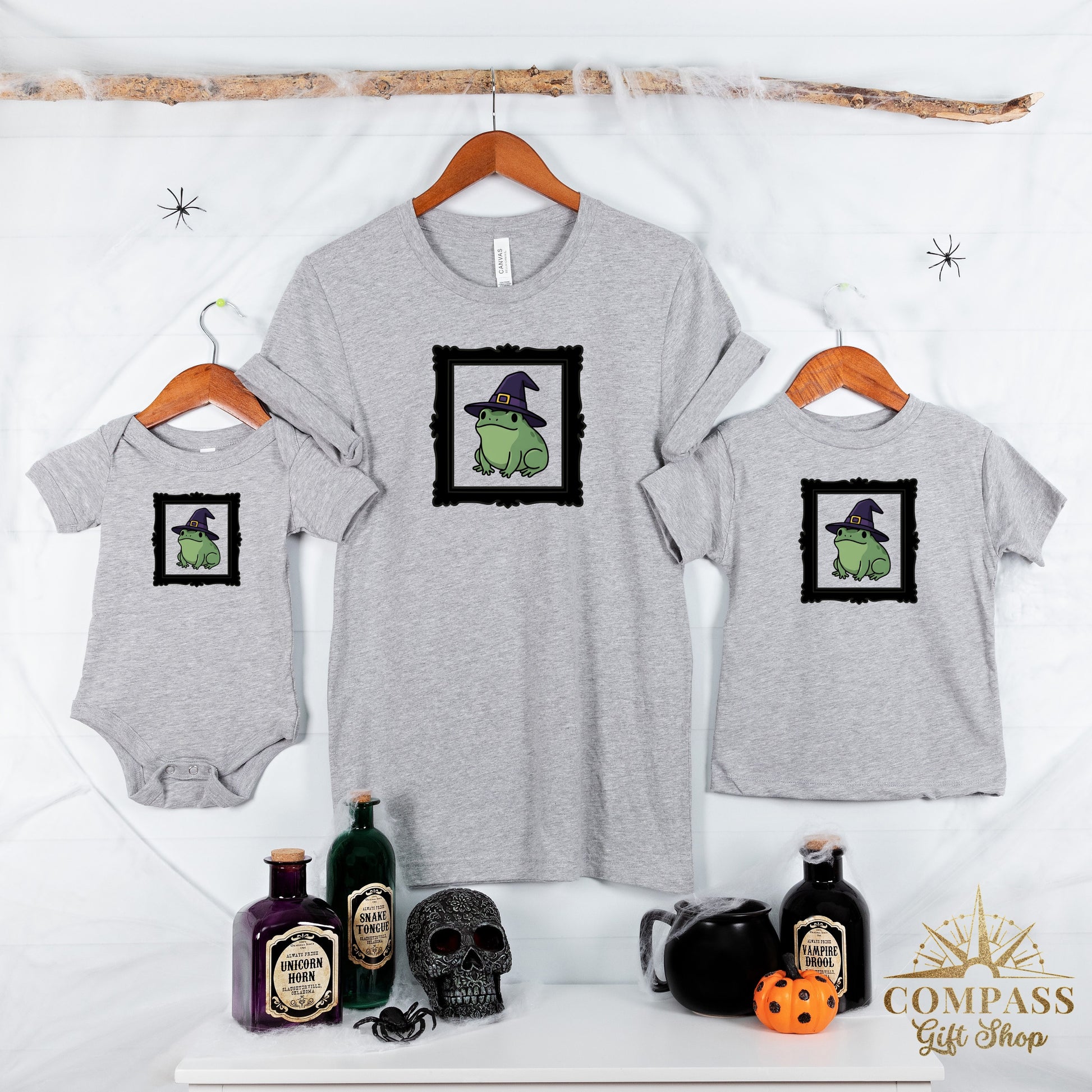 Grey t-shirts and a bodysuit feature a frog in a witch hat graphic.