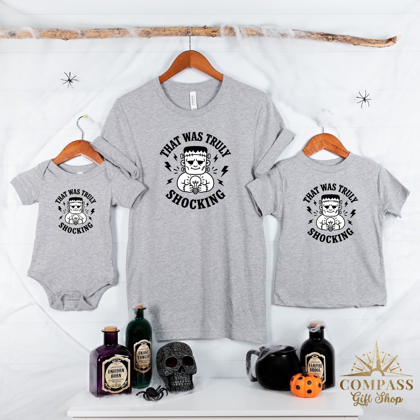 Grey t-shirts and baby onesie with Frankenstein and lightbulb graphic stating "That was truly shocking".