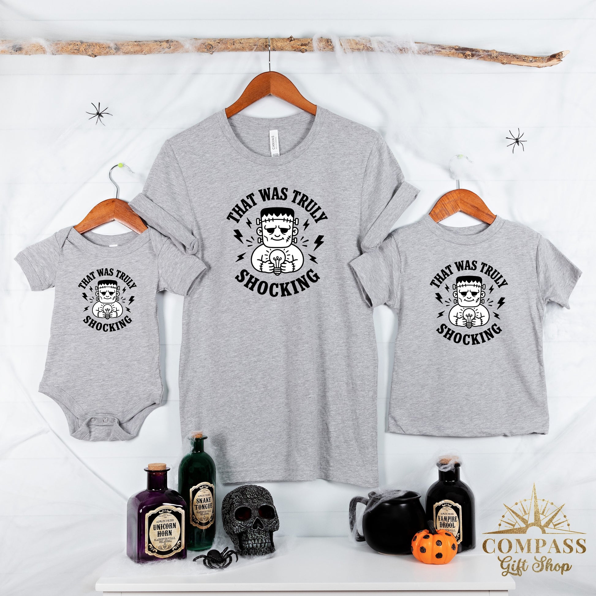 Grey t-shirts and baby onesie with Frankenstein and lightbulb graphic stating "That was truly shocking".
