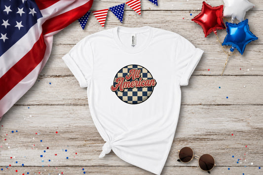 White t-shirt with "All American" in a checkered circle, on wooden background.