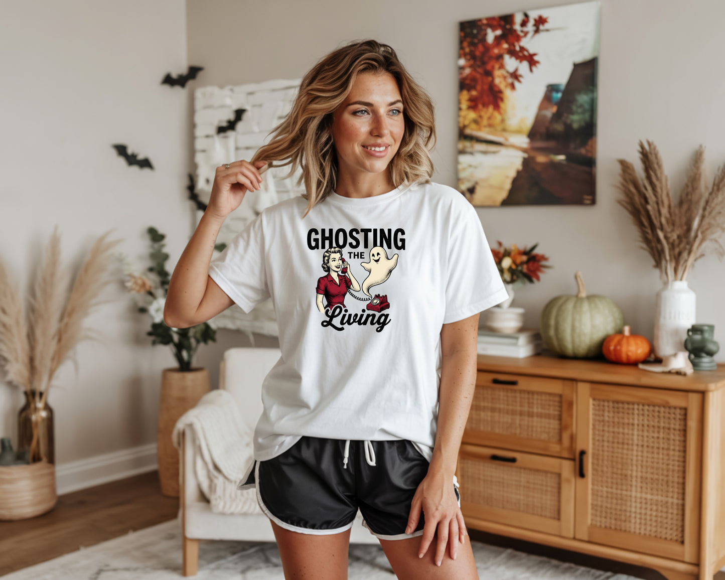 White t-shirt with "Ghosting the Living" graphic featuring a woman and ghost on a phone.
