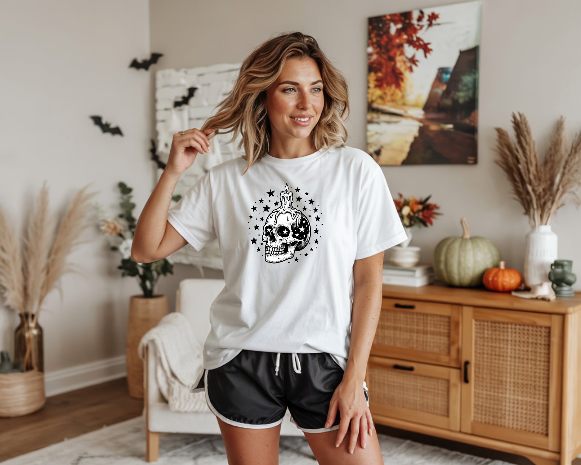 White t-shirt with black skull and candle graphic, surrounded by stars.