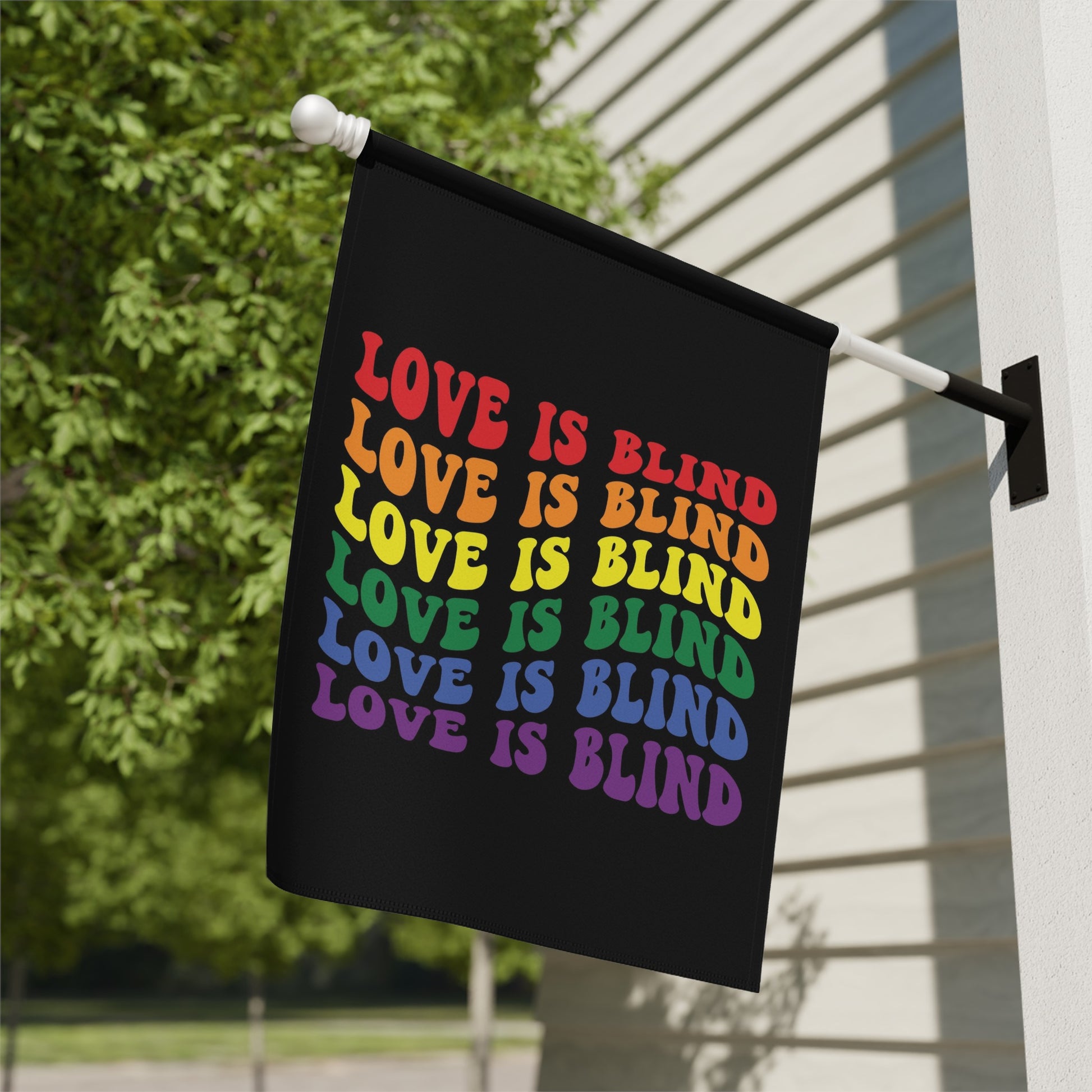 Black flag with rainbow text reading "LOVE IS BLIND" repeated.