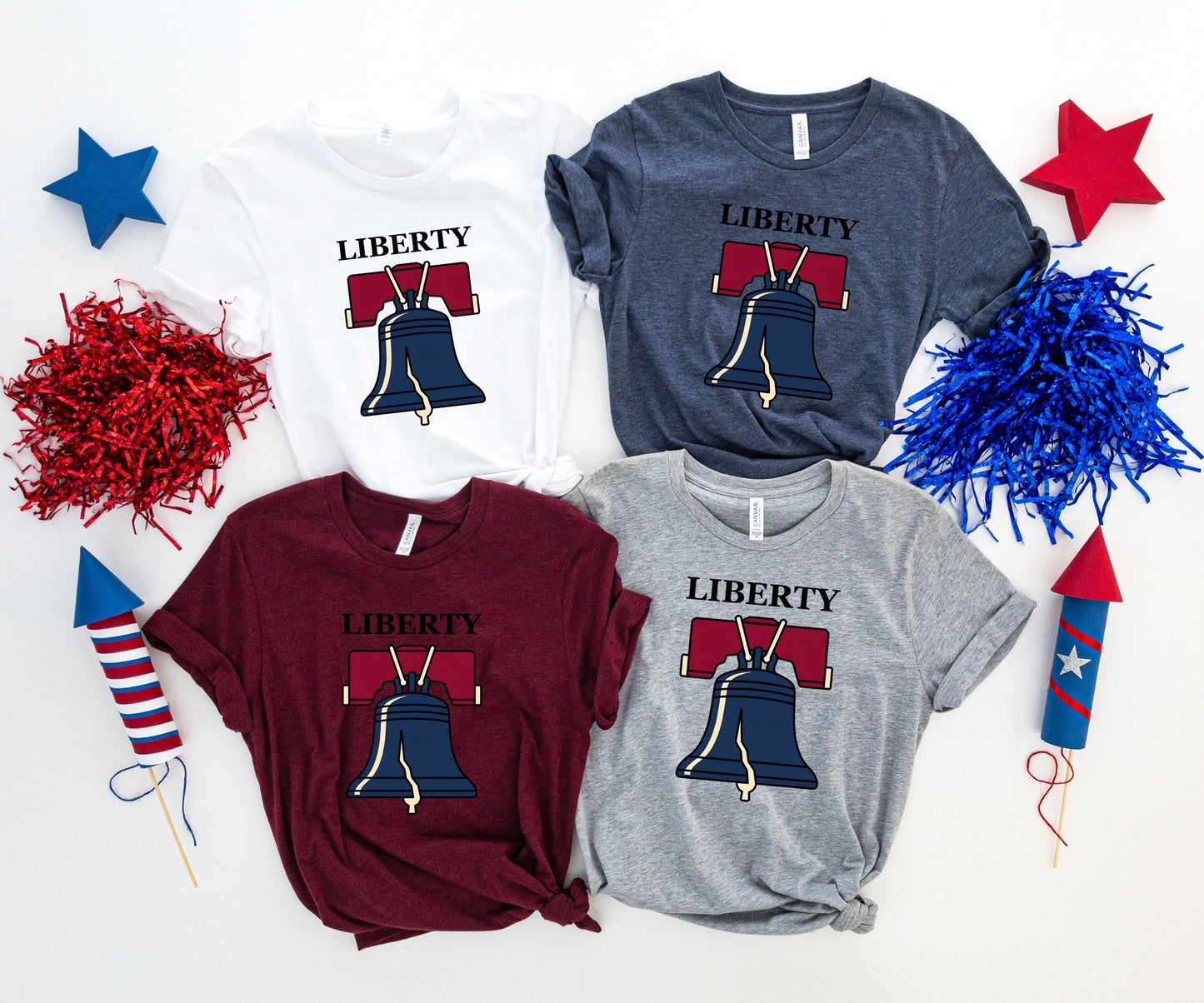 Four Liberty Bell t-shirts in white, dark blue, burgundy, and grey.