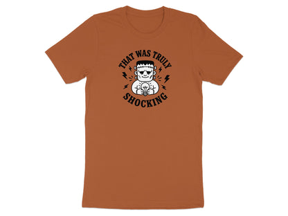 Frankenstein monster holding a lightbulb on an orange t-shirt with "That Was Truly Shocking" text.