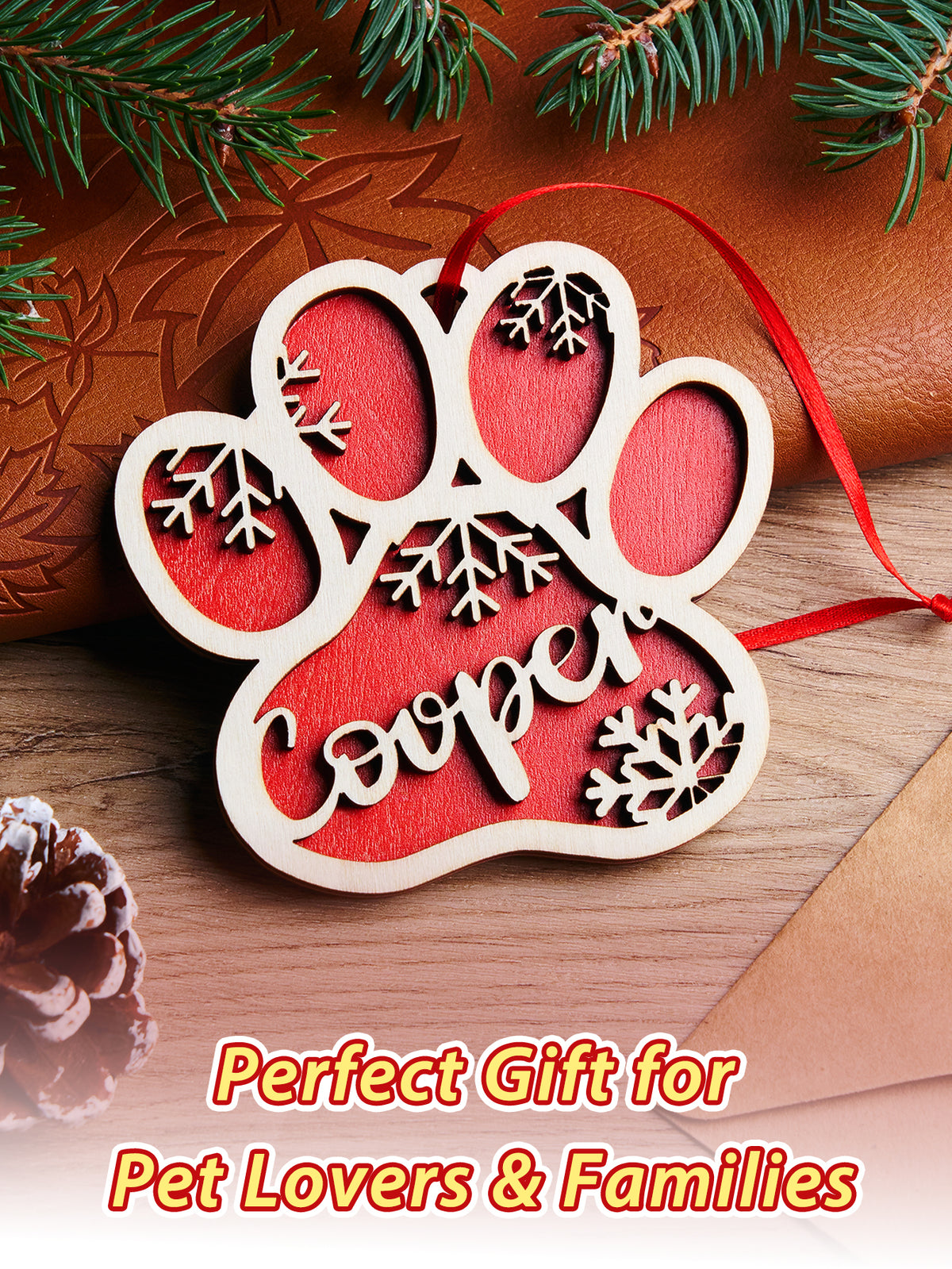 Decorative paw print ornament with 'Cooper' on a wooden surface with Christmas decorations.