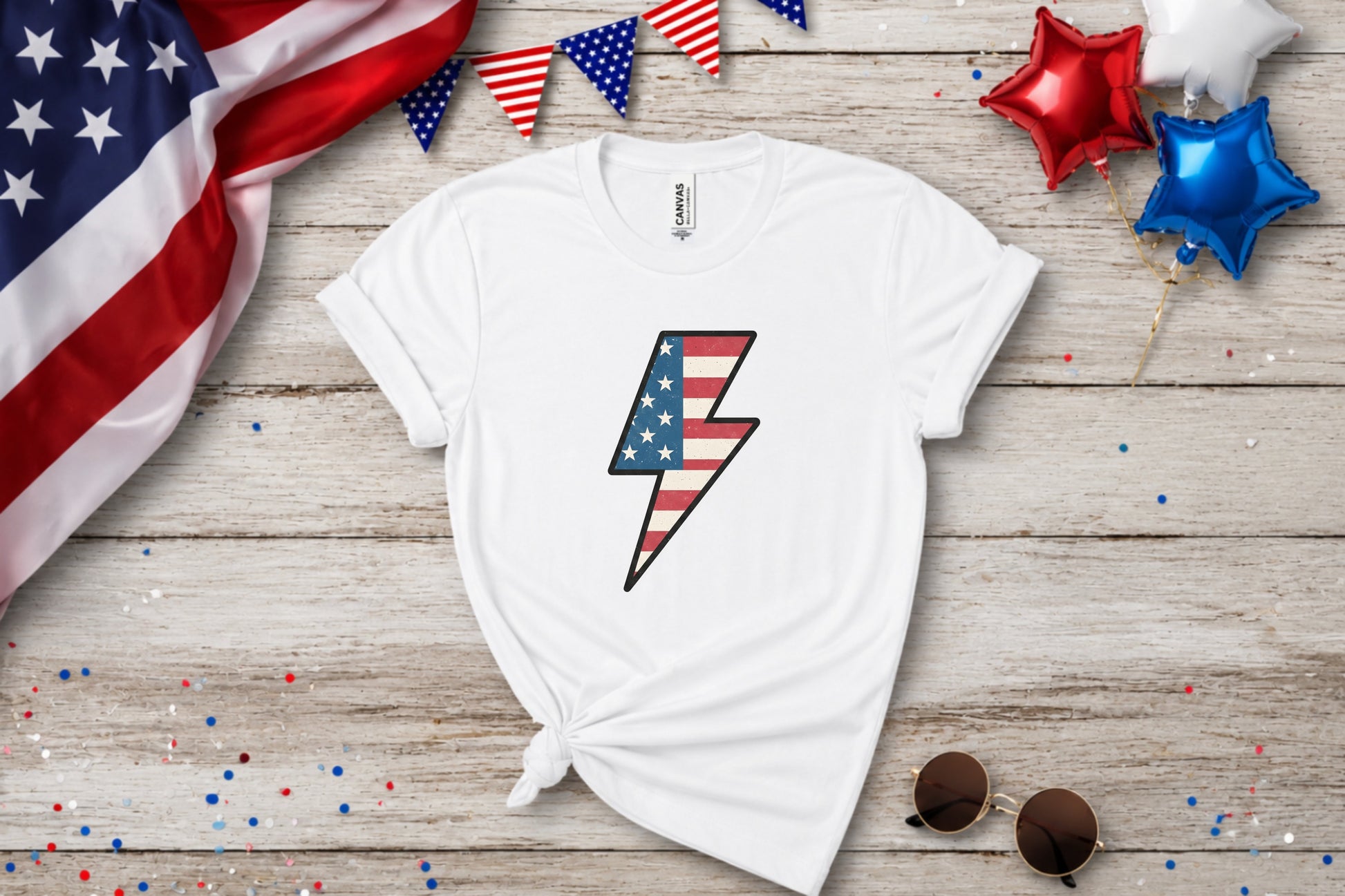 White t-shirt with American flag lightning bolt graphic, patriotic decorations.