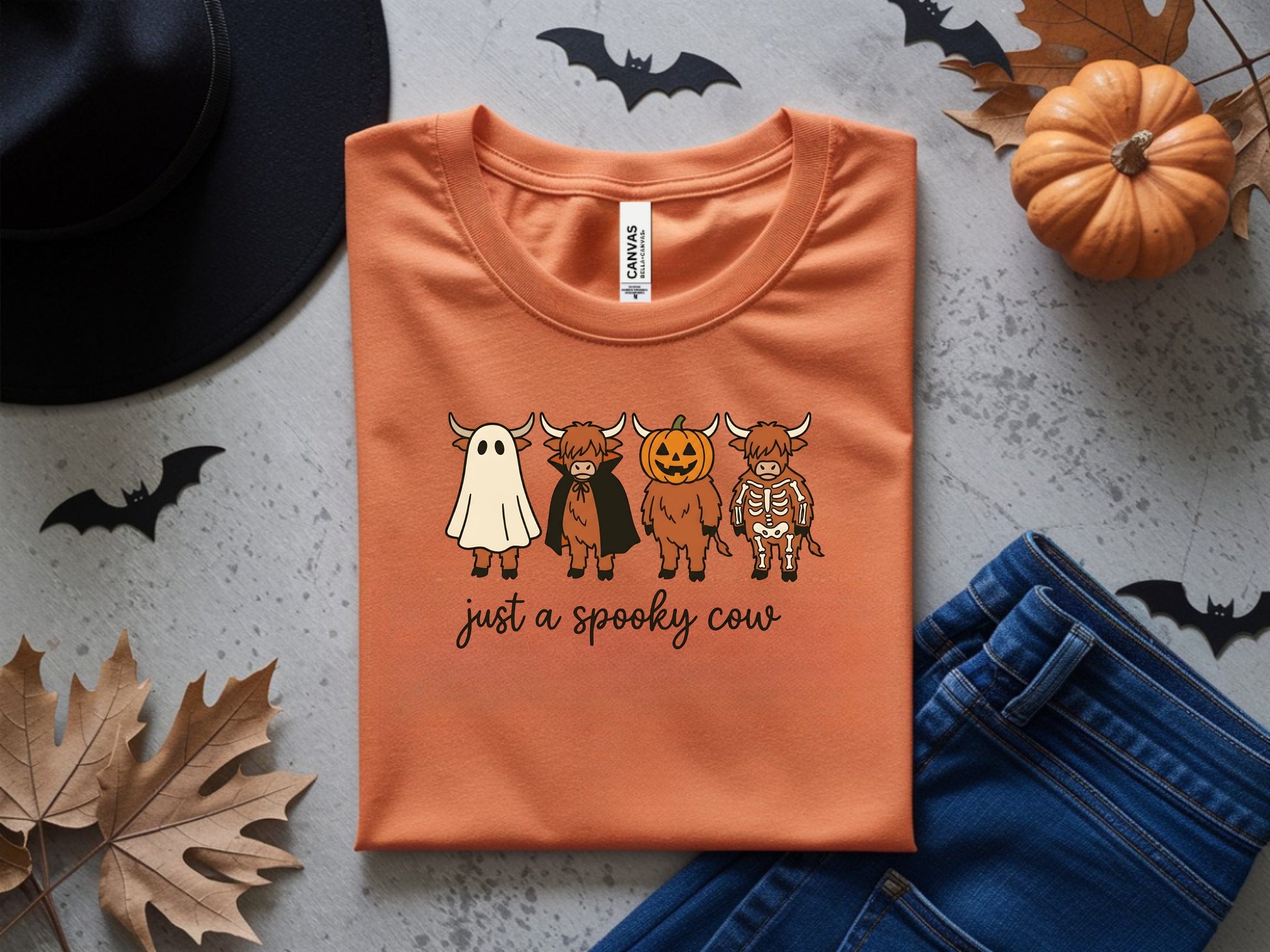 Orange t-shirt with "just a spooky cow" and four Halloween-themed highland cows.