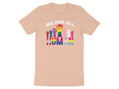 Rainbow pride fists above text "WE ARE ALL HUMAN" on a peach t-shirt.