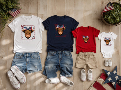 T-shirts and denim shorts with patriotic cow designs arranged on wood.