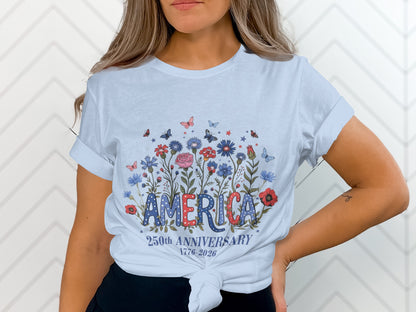 White t-shirt with "AMERICA" in floral letters and "250TH ANNIVERSARY 1776-2026" below.
